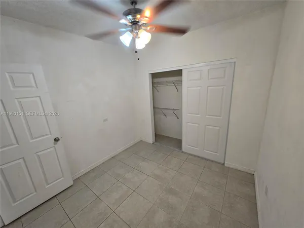 wooden floor in an empty room with a chandelier fan