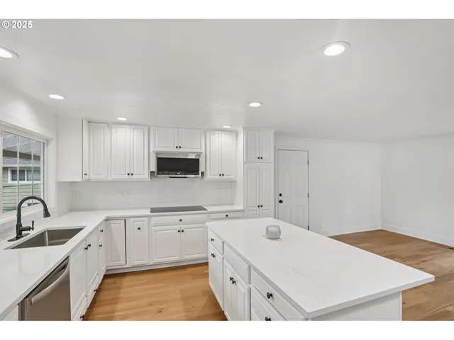 a kitchen with a sink a stove a refrigerator and white cabinets