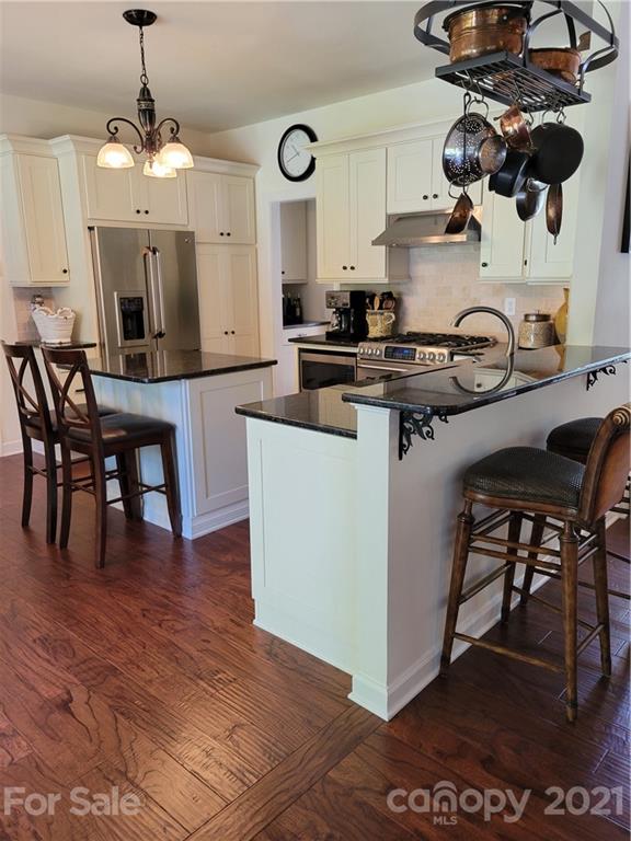 311 Matthews Estates Road Matthews, NC 28105 - Photo 10 of 27 a kitchen with stainless steel appliances granite countertop a stove top oven a dining table and chairs with wooden floor