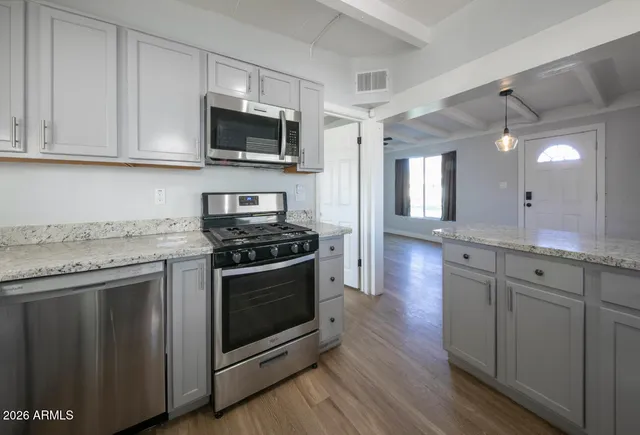 a kitchen with stainless steel appliances granite countertop a stove a sink and a microwave