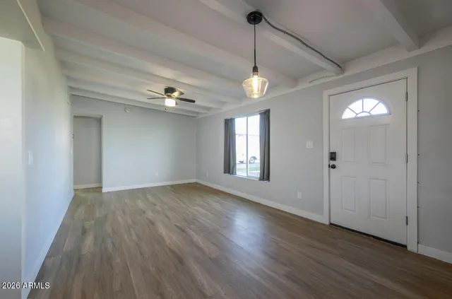 a view of an empty room with wooden floor and a window