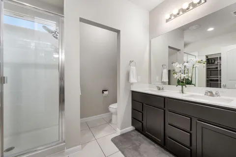 a bathroom with a double vanity sink a toilet and a mirror