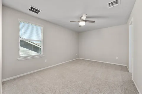 an empty room with a window and ceiling fan
