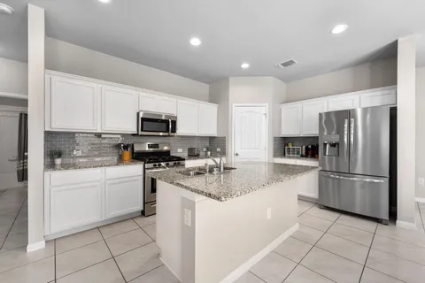 a kitchen with granite countertop a refrigerator and white cabinets