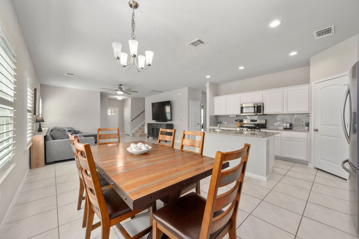 6701 Janes Ranch Road Austin, TX 78744 - Photo 8 of 36 a dining room with kitchen island a dining table wooden floor and a kitchen view
