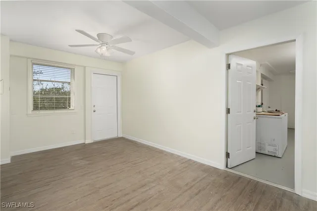 an empty room with wooden floor closet and windows