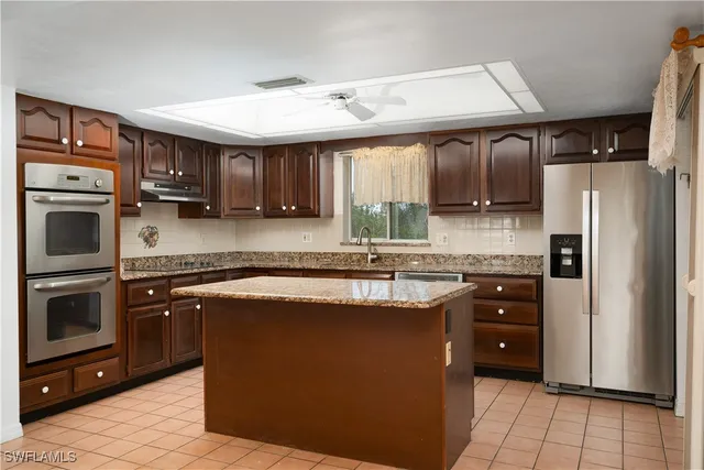 a kitchen with stainless steel appliances granite countertop a stove a sink and a refrigerator