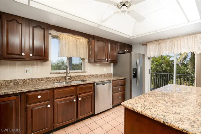 a kitchen with stainless steel appliances granite countertop sink refrigerator and cabinets