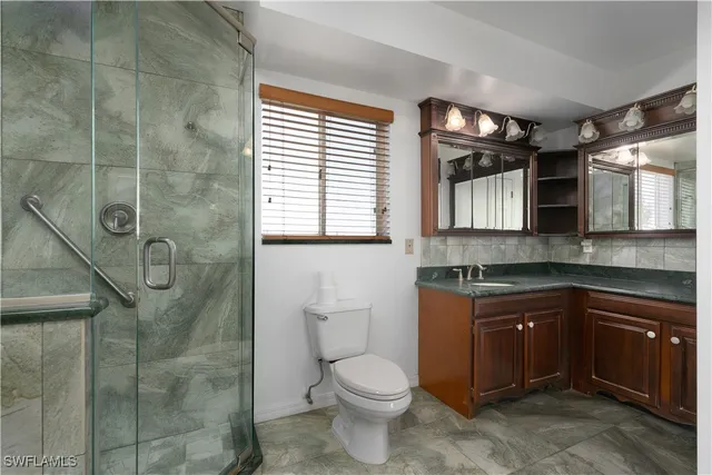 a bathroom with a granite countertop sink toilet and shower