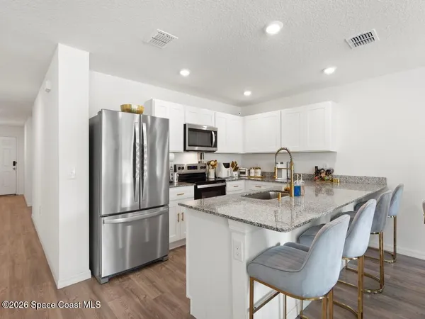 a kitchen with refrigerator and chairs