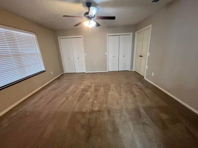 an empty room with windows and fan