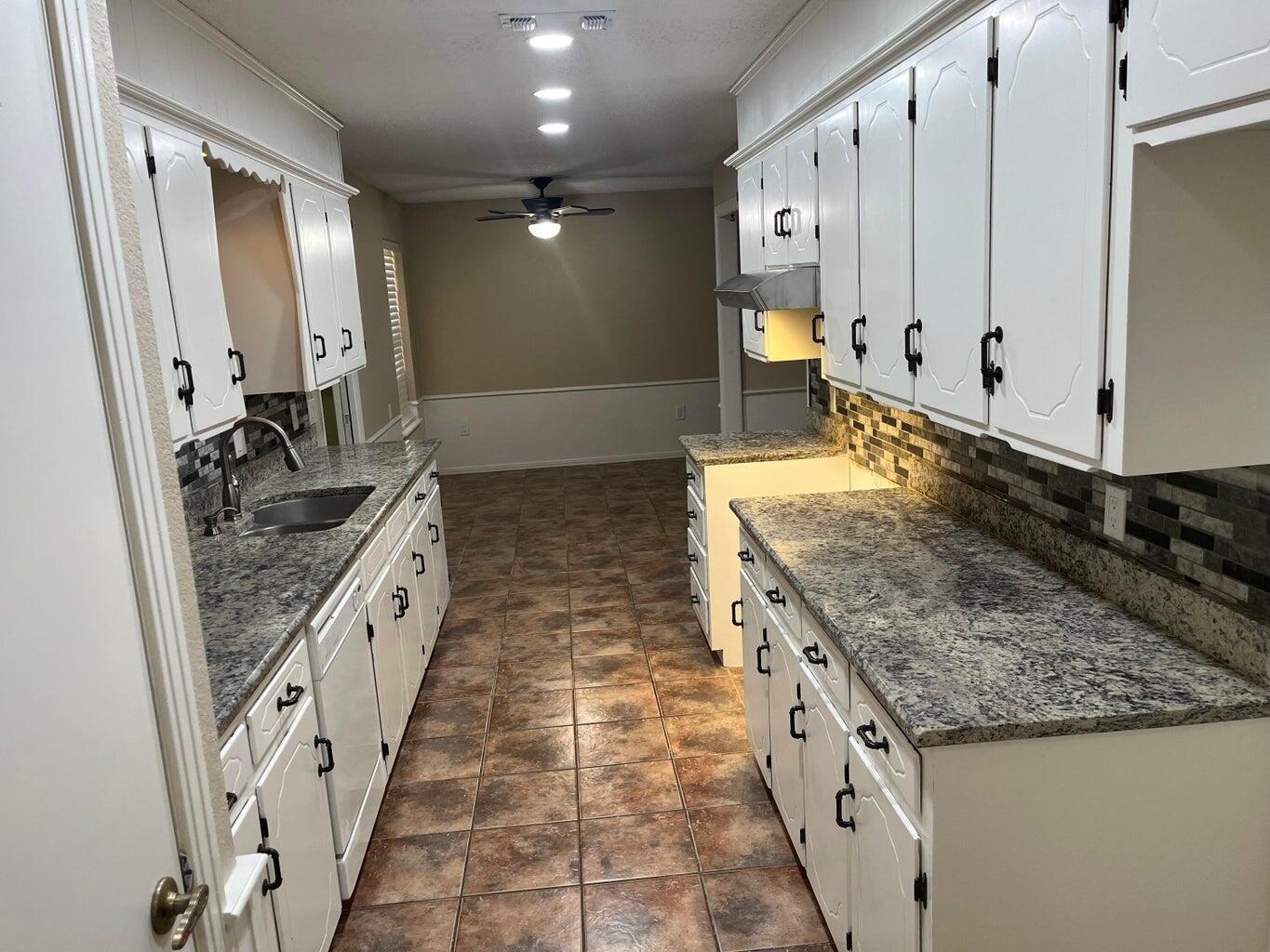 1312 Yonkers Street Plainview, TX 79072 - Photo 10 of 25 a large kitchen with granite countertop a sink and dishwasher a stove top oven with wooden floor