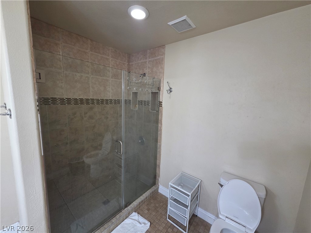 3381 Westwind Road Las Vegas, NV 89146 - Photo 26 of 52 A well-lit, tiled shower with a glass enclosure enhances this modern bathroom space.