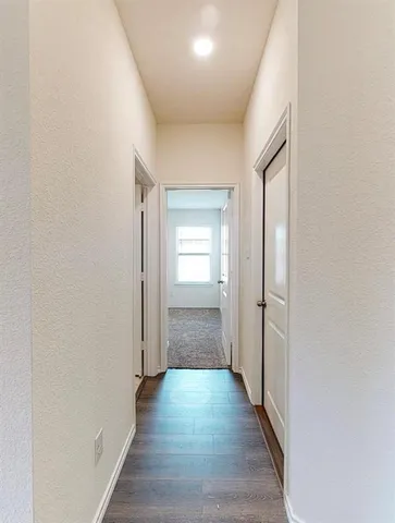 a view of a hallway with wooden floor and closet