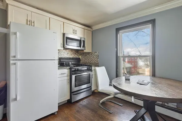 a kitchen with stainless steel appliances a stove a refrigerator a sink a dining table and chairs