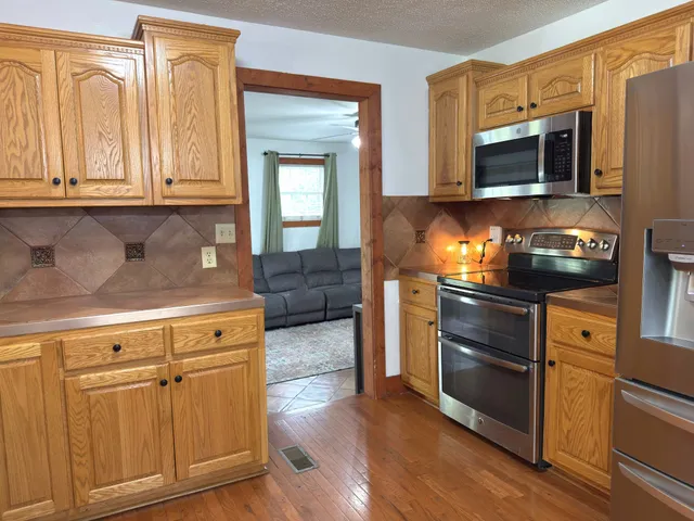 a kitchen with stainless steel appliances granite countertop a sink a stove cabinets and wooden floor