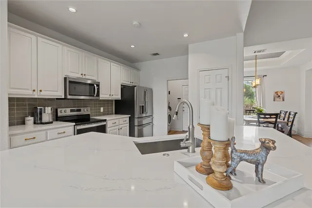 a kitchen with stainless steel appliances kitchen island granite countertop a refrigerator a stove a sink a dining table and chairs with wooden floor