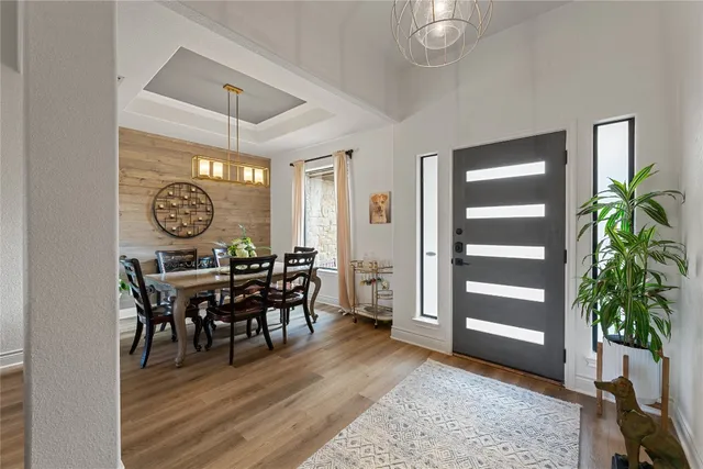 a view of a dining room and livingroom with furniture wooden floor a rug a potted plant and a chandelier