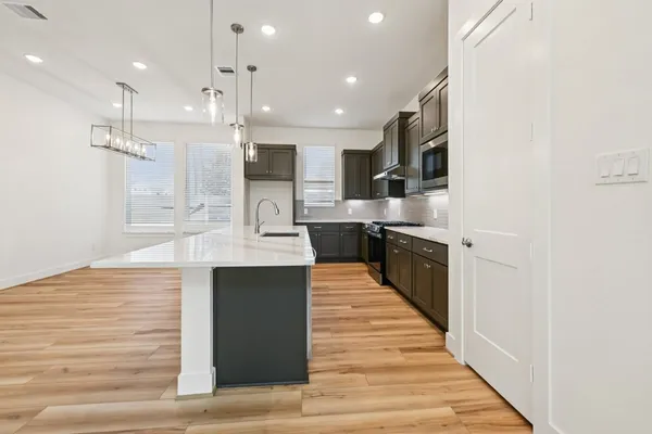 a large kitchen with stainless steel appliances kitchen island a large counter top and a wooden floor