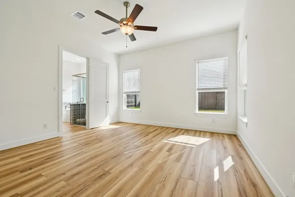 an empty room with wooden floor and windows