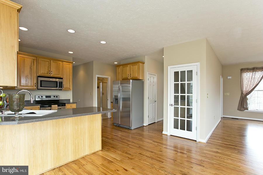 176 White Hall Road Winchester, VA 22603 - Photo 12 of 30 a kitchen with stainless steel appliances granite countertop a refrigerator a stove top oven a sink and dishwasher with wooden floor