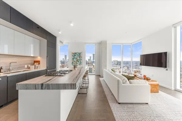 a living room with stainless steel appliances kitchen island granite countertop a couch a dining table and chairs