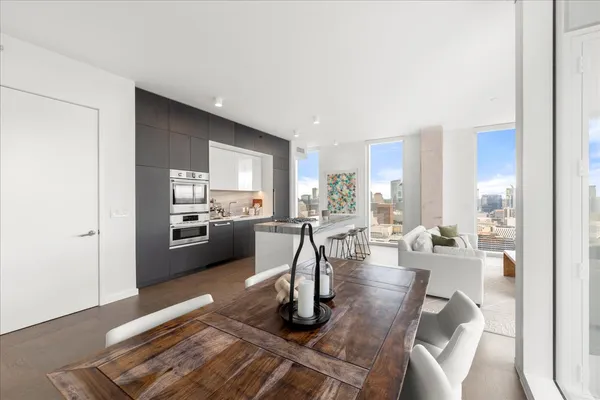 a living room with couches and kitchen view with wooden floor