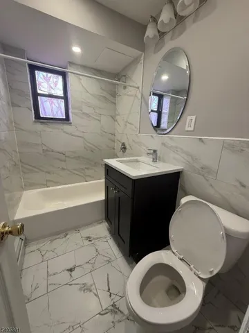a bathroom with a toilet sink vanity granite and mirror