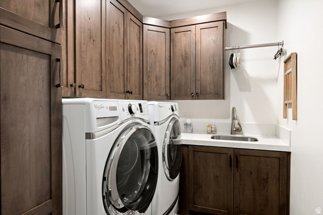 11547 Soaring Hawk Lane Hideout, UT 84036 - Photo 21 of 43 Dedicated laundry area featuring a front-load washer and dryer, extensive wood-finish cabinetry, a white countertop, and an undermount sink with a gooseneck faucet