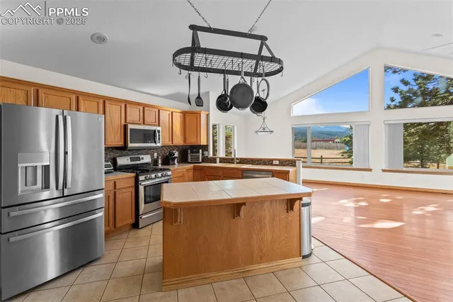 a kitchen with stainless steel appliances granite countertop a sink a stove top oven a refrigerator cabinets and a window