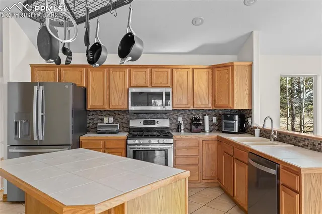 a kitchen with stainless steel appliances a stove a sink a microwave a refrigerator and cabinets