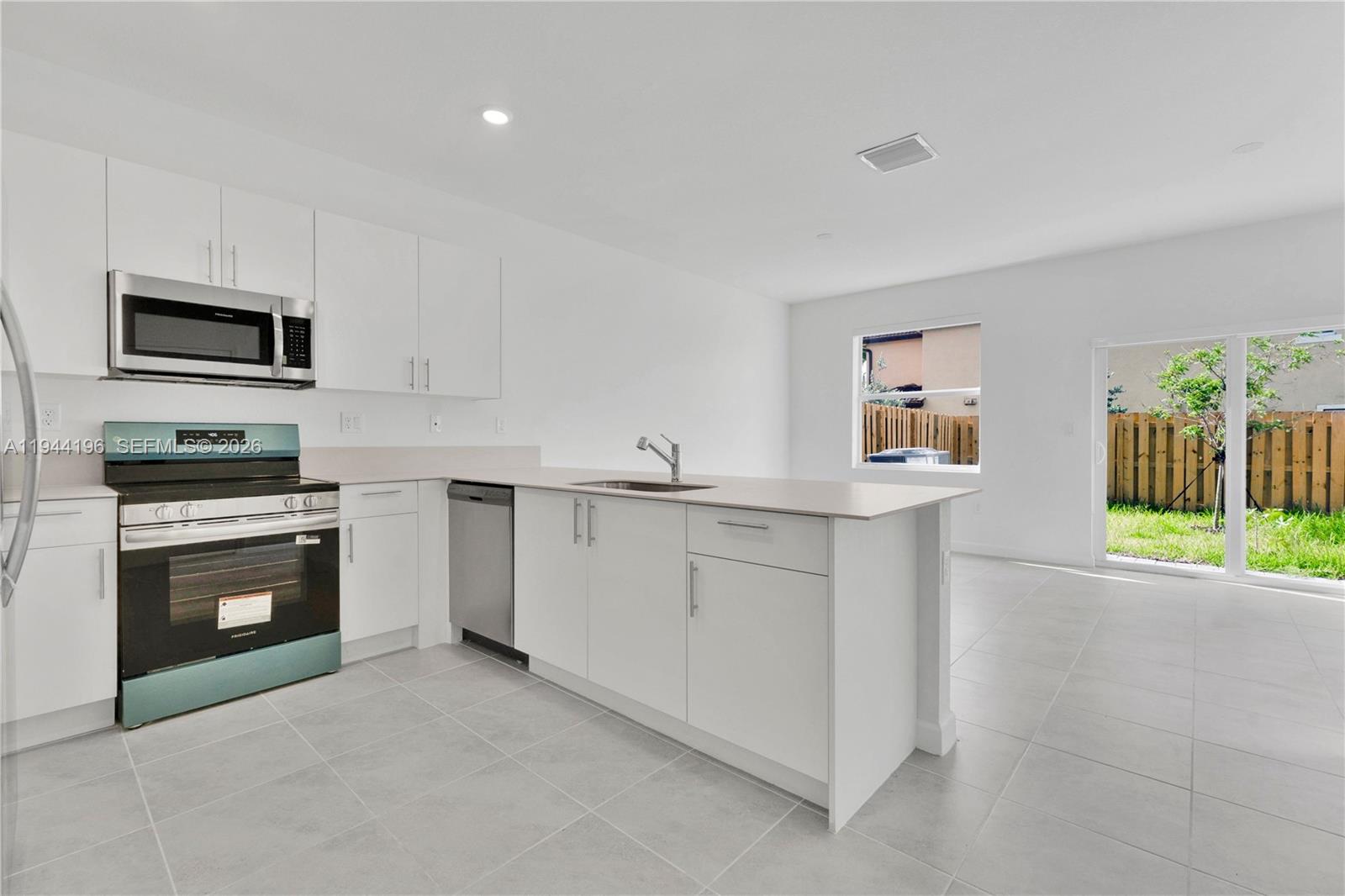12168 Southwest 268th Street Homestead, FL 33032 - Photo 6 of 27 a kitchen with granite countertop white cabinets and stainless steel appliances