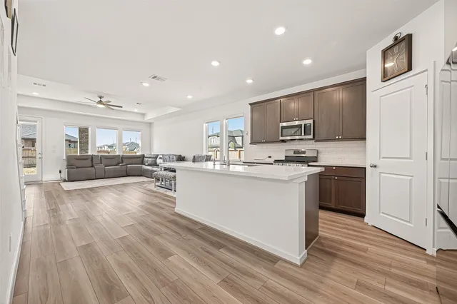 a kitchen with stainless steel appliances granite countertop a stove top oven a sink and a refrigerator