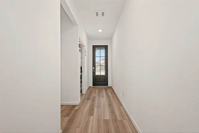 a view of a hallway with wooden floor and a bathroom