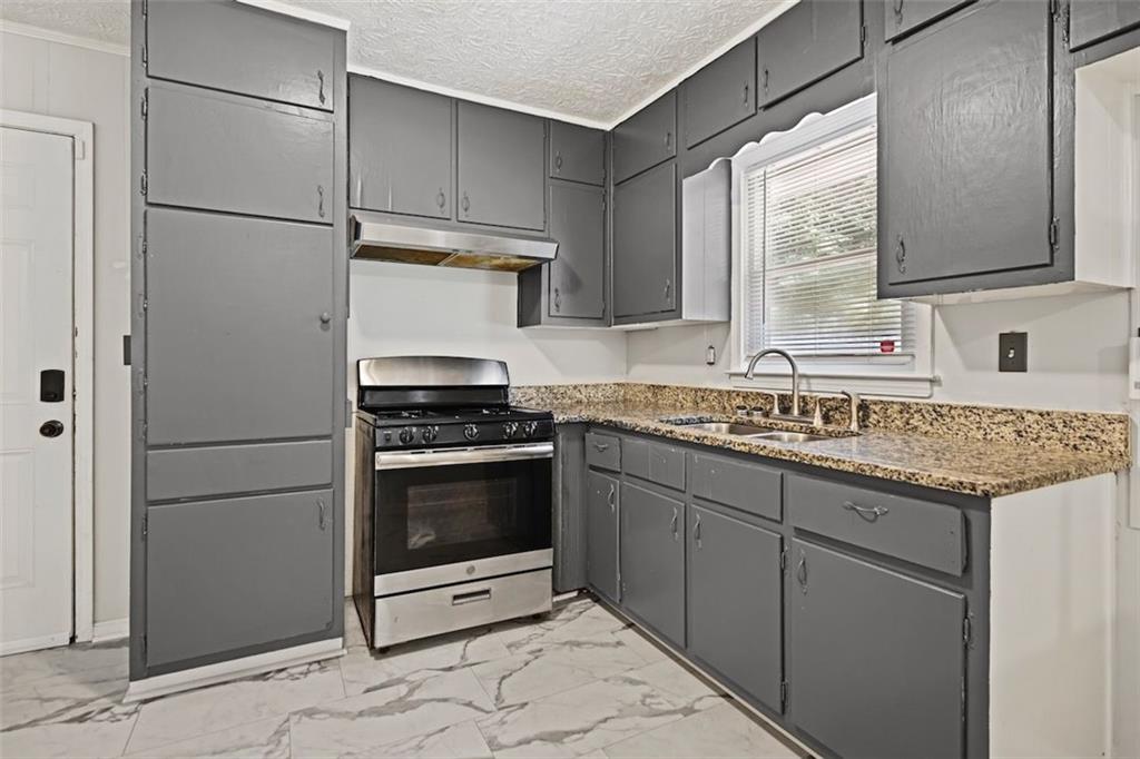 7039 Rockbridge Road Southwest Stone Mountain, GA 30087 - Photo 9 of 28 a kitchen with granite countertop a sink stainless steel appliances and cabinets