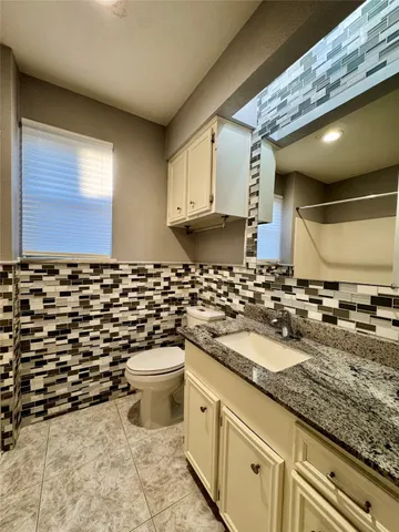 a bathroom with a granite countertop sink and a toilet
