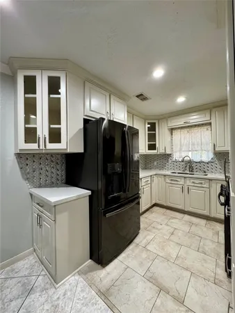 a kitchen with a stove a refrigerator and white cabinets