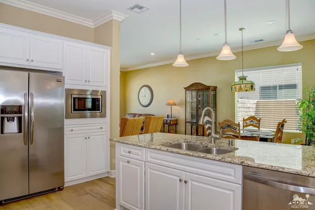 a kitchen with stainless steel appliances granite countertop a sink a refrigerator and a window