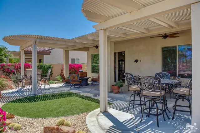 a view of a patio with table and chairs potted plants and a large tree
