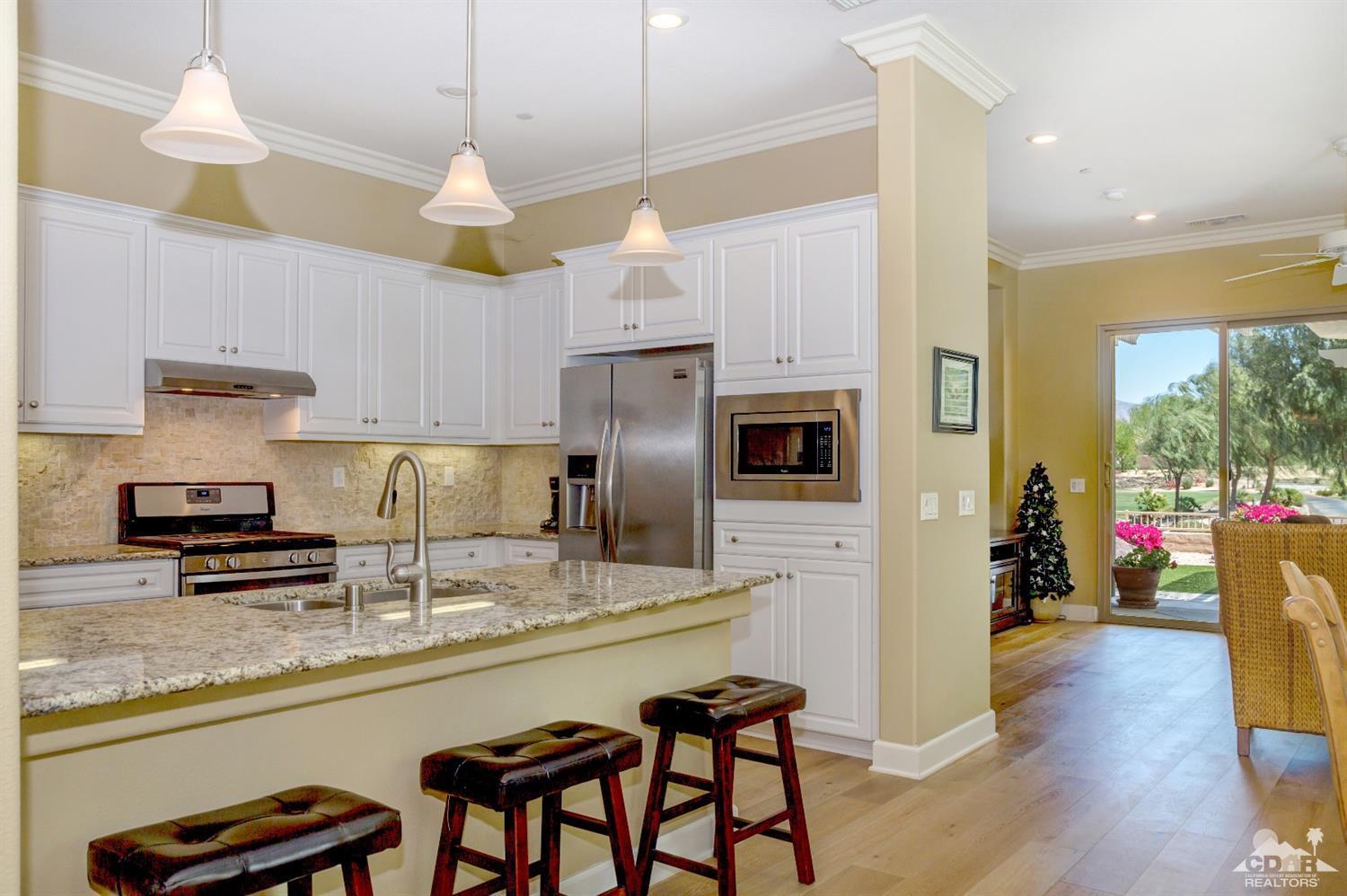 81340 Corte Compras Indio, CA 92203 - Photo 9 of 43 a kitchen with stainless steel appliances granite countertop a refrigerator a sink dishwasher a stove and a dining table with wooden floor