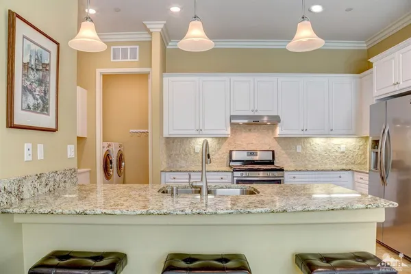 a kitchen with kitchen island granite countertop a stove a sink and a cabinets