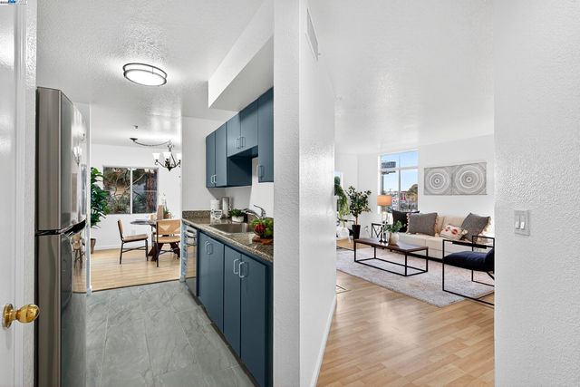 a kitchen with stainless steel appliances a refrigerator a stove a sink a dining table and chairs with wooden floor