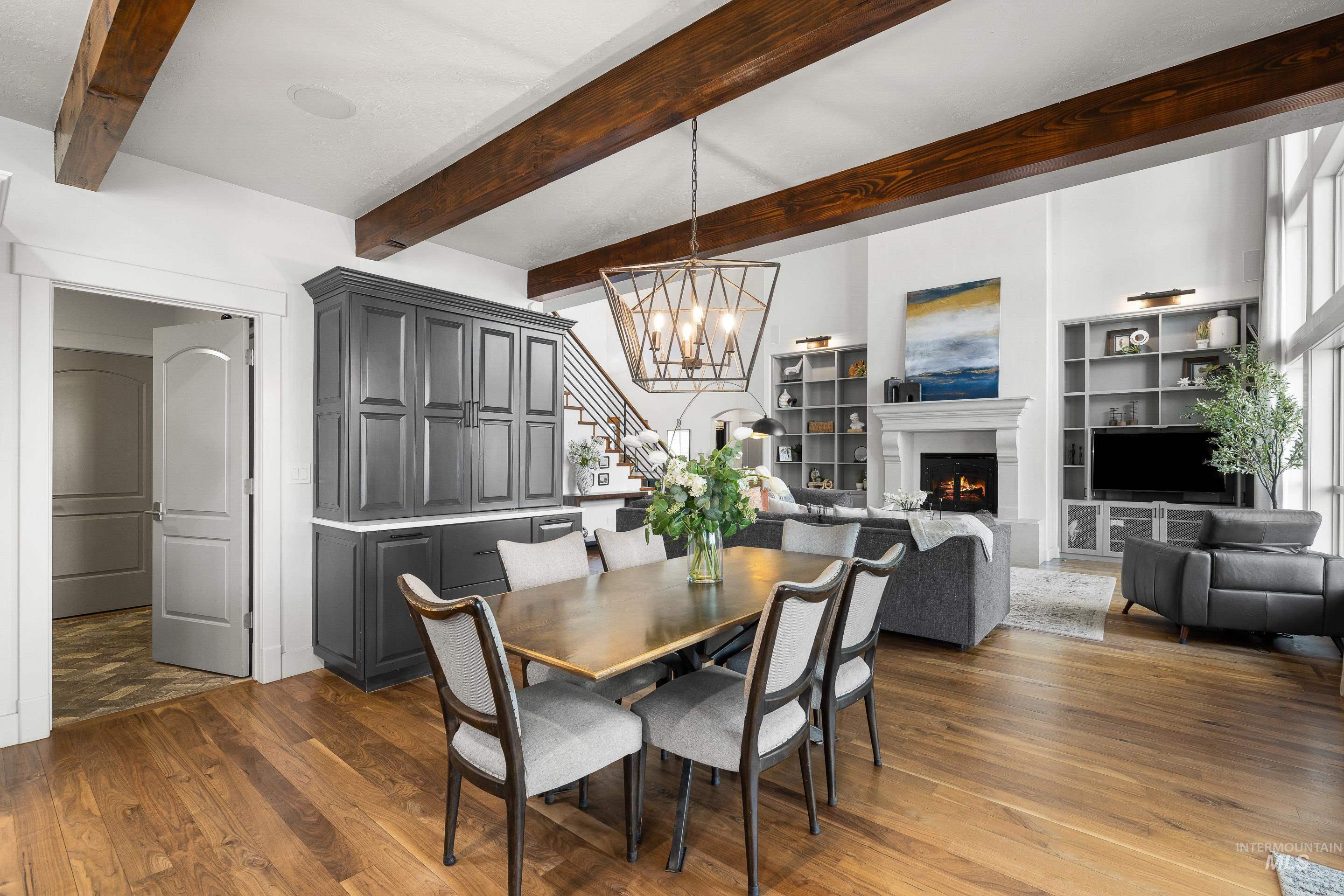 1166 East Rivers End Drive Eagle, ID 83616 - Photo 16 of 50 Dining space featuring suspended lighting, dark wood-style flooring, a warm lit fireplace, and beamed ceiling