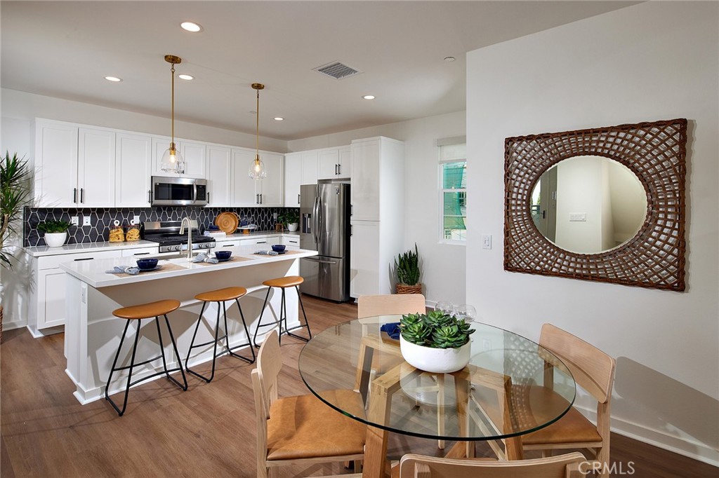 a kitchen with kitchen island granite countertop a sink a stove a dining table and chairs