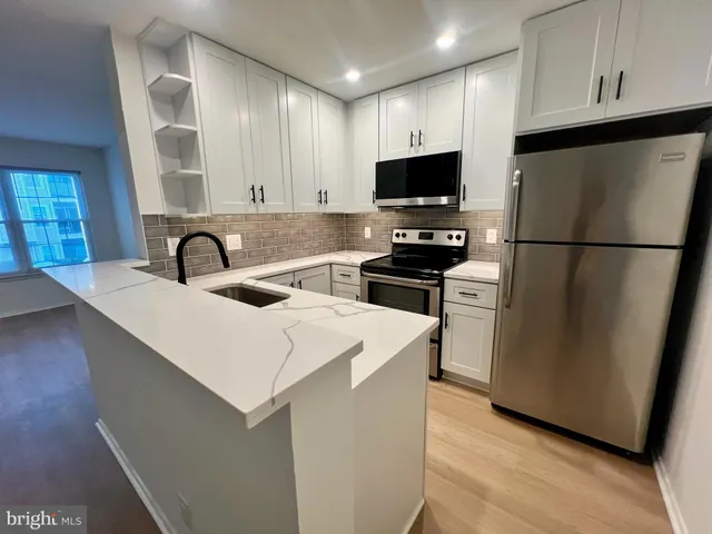 a kitchen with stainless steel appliances a microwave a sink a stove a refrigerator and white cabinets