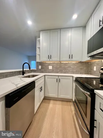 a large kitchen with stainless steel appliances a large window a oven a sink and a refrigerator