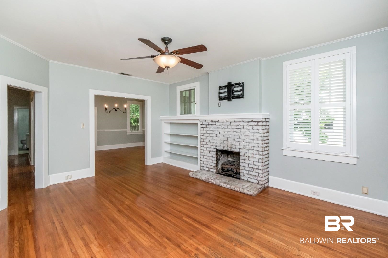 10 Macy Place Mobile, AL 36604 - Photo 3 of 43 Unfurnished living room with hanging lights, ceiling fan, wood finished floors, a brick fireplace, and ornamental molding