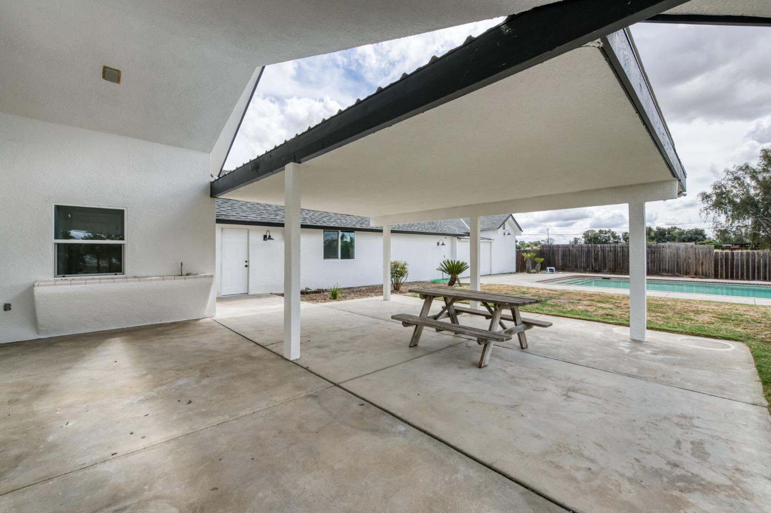 16564 Monreal Road Madera, CA 93636 - Photo 34 of 59 a view of a patio with table and chairs under an umbrella