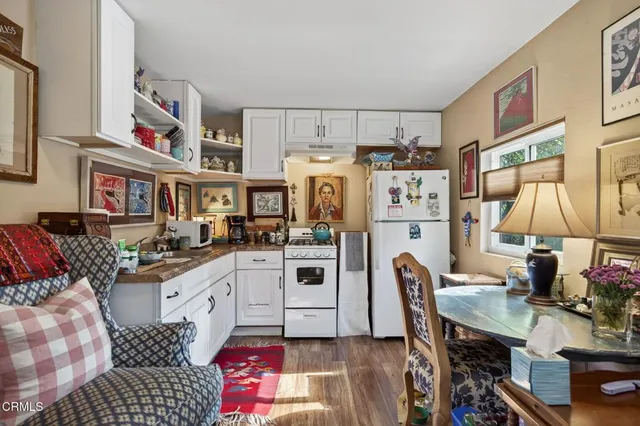 a kitchen with stainless steel appliances a stove a refrigerator a sink dishwasher and a dining table with wooden floor