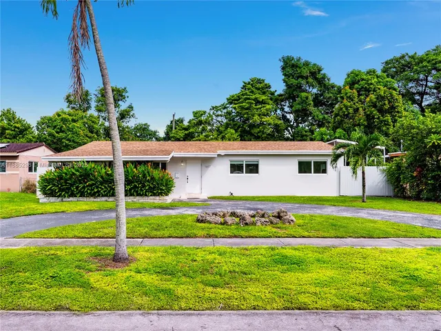 a view of a house with a yard and palm trees
